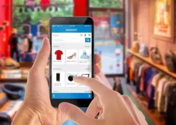 Ilustrasi seseorang memilih produk pakaian dan kamera di aplikasi marketplace melalui smartphone untuk belanja online jelang lebaran.