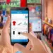 Ilustrasi seseorang memilih produk pakaian dan kamera di aplikasi marketplace melalui smartphone untuk belanja online jelang lebaran.