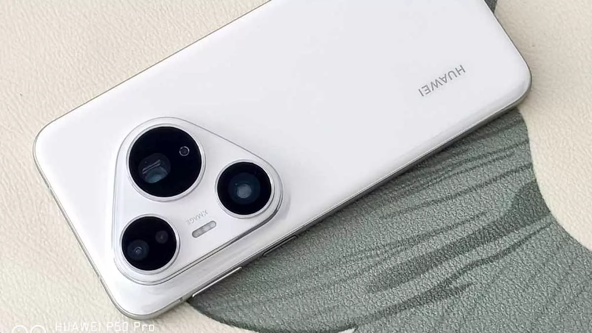 Pandangan atas bodi belakang Huawei Pura 90 Pro warna putih di atas permukaan bertekstur, menampilkan logo "HUAWEI" dan modul kamera XMAGE berbentuk segitiga dengan tiga lensa.