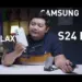 Seorang reviewer pria memegang HP Samsung Galaxy S24 FE putih krem di studio video, menunjuk ponsel tersebut sambil membahas harga Samsung Galaxy S24 FE di tahun 2026 yang turun drastis, menjadikannya pilihan worth it untuk dibeli dengan uang THR Lebaran.