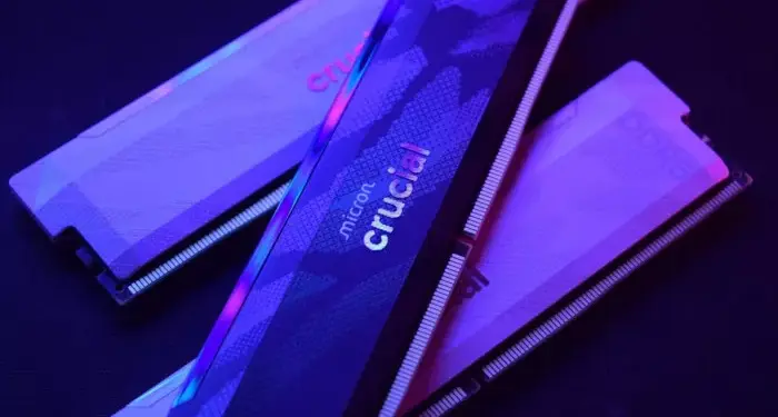Tiga keping RAM DDR5 merk Crucial dengan pencahayaan neon ungu kebiruan.