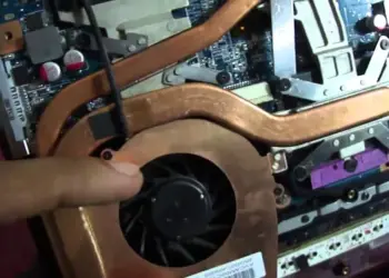 Komponen heatsink tembaga dan kipas laptop yang terpasang di dalam casing.