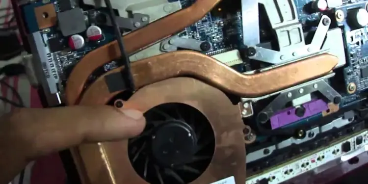 Komponen heatsink tembaga dan kipas laptop yang terpasang di dalam casing.
