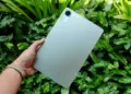 Seseorang memegang tablet Xiaomi Redmi Pad 2 SE dengan latar belakang daun yang segar.