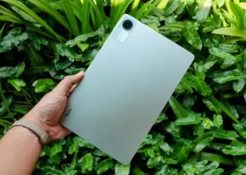 Seseorang memegang tablet Xiaomi Redmi Pad 2 SE dengan latar belakang daun yang segar.