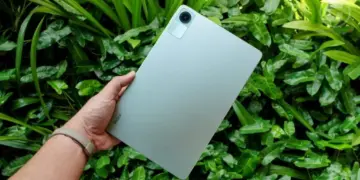 Seseorang memegang tablet Xiaomi Redmi Pad 2 SE dengan latar belakang daun yang segar.