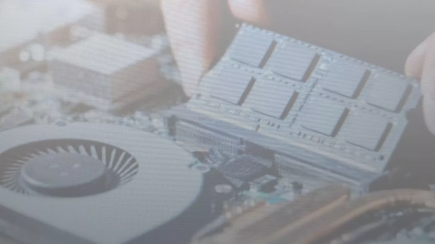 Seseorang memasang atau memeriksa modul RAM di dekat area kipas laptop.