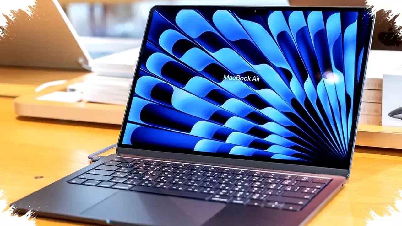 Tampilan layar MacBook Air dengan wallpaper biru abstrak di atas meja kayu.