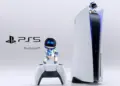 Karakter Astro Bot berdiri di atas konsol dan controller PS5 dengan logo PlayStation 5 di sampingnya.