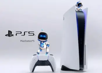 Karakter Astro Bot berdiri di atas konsol dan controller PS5 dengan logo PlayStation 5 di sampingnya.
