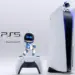 Karakter Astro Bot berdiri di atas konsol dan controller PS5 dengan logo PlayStation 5 di sampingnya.