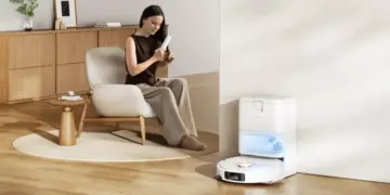 Seorang wanita bersantai di ruang tamu saat Robot Vacuum Xiaomi H50 Series kembali ke stasiun pengisian otomatisnya.