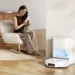 Seorang wanita bersantai di ruang tamu saat Robot Vacuum Xiaomi H50 Series kembali ke stasiun pengisian otomatisnya.