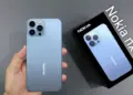 Seseorang memegang smartphone Nokia NX 5G berwarna biru muda beserta kotak kemasan yang menampilkan gambar produk.