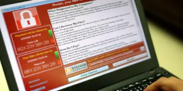 Layar laptop menampilkan serangan ransomware WannaCry dengan teks 'Ooops, your files have been encrypted!' dan permintaan tebusan Bitcoin.