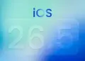 Wallpaper bertuliskan iOS 26.5 dengan nuansa warna biru dan hijau toska yang futuristik.