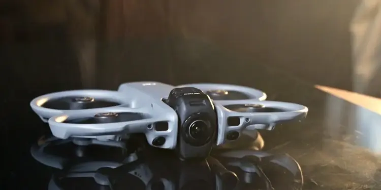 Detail desain bodi drone DJI Avata 360 yang futuristik diletakkan di permukaan reflektif.