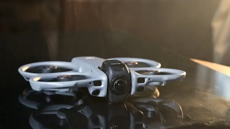 Detail desain bodi drone DJI Avata 360 yang futuristik diletakkan di permukaan reflektif.