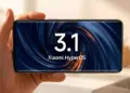 Seseorang memegang smartphone Xiaomi berlayar lengkung yang menampilkan logo Xiaomi HyperOS 3.1 dalam posisi lanskap.