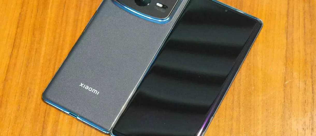 Bodi belakang dan layar sekunder HP lipat premium Xiaomi Mix Fold 5 yang diletakkan di atas meja kayu.