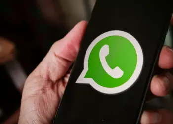 Seseorang memegang smartphone yang menampilkan logo aplikasi WhatsApp di layar untuk reservasi username baru.