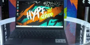 Laptop Axioo Hype Series varian Intel Core i3 dengan wallpaper bertuliskan Hype Series diletakkan di atas meja kaca.