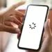Layar smartphone menampilkan ikon loading berputar yang menandakan HP sering lemot saat membuka aplikasi.