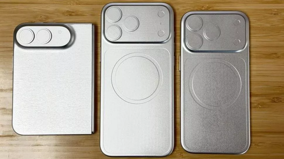 Tiga cetakan dummy logam iPhone 18 series yang memperlihatkan perbedaan ukuran perangkat dan cetakan lingkaran MagSafe di atas meja kayu.