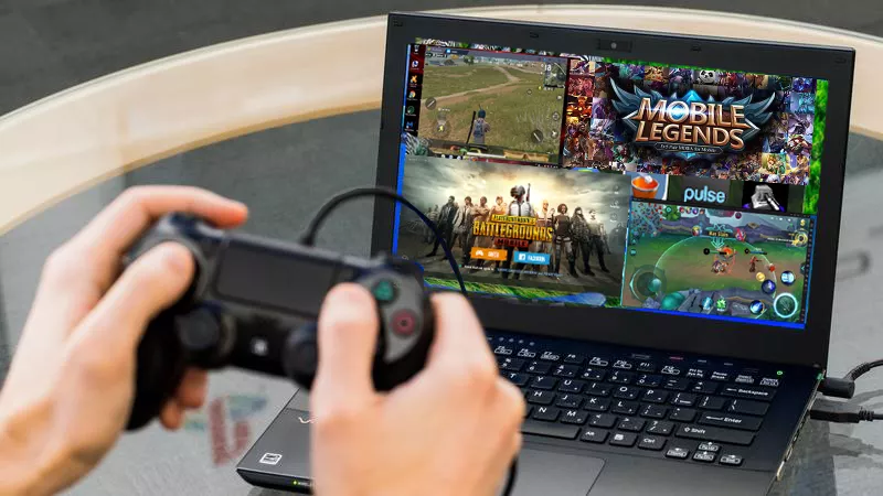 Sepasang tangan memegang gamepad stik hitam untuk main Mobile Legends di laptop