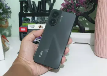 Seseorang memegang smartphone POCO warna hitam abu-abu gelap dengan dua lingkaran kamera besar, pilihan HP memori 512GB terjangkau.