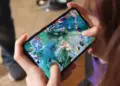 Seseorang sedang memegang smartphone dan asyik bermain game Mobile Legends di peta Land of Dawn.