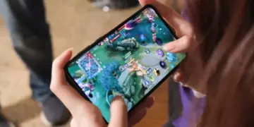 Seseorang sedang memegang smartphone dan asyik bermain game Mobile Legends di peta Land of Dawn.