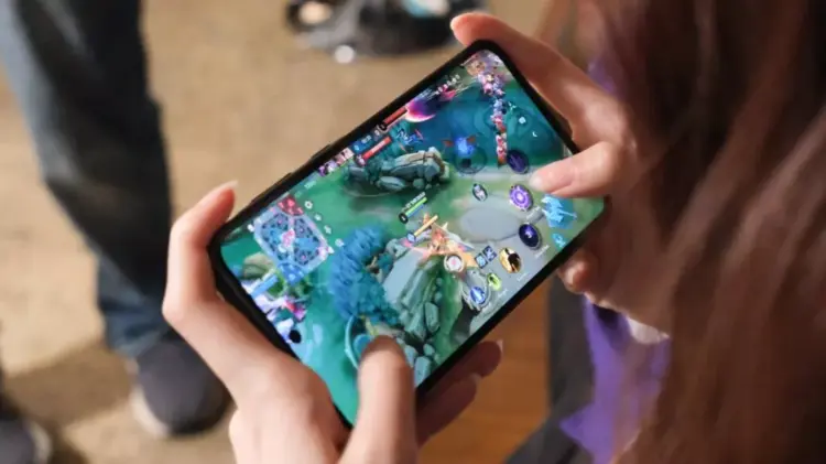 Seseorang sedang memegang smartphone dan asyik bermain game Mobile Legends di peta Land of Dawn.