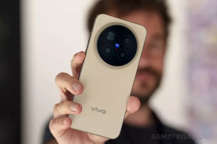 Seseorang sedang memegang Vivo X500 Pro Max varian warna gold, memperlihatkan detail modul kamera Zeiss T* secara langsung.