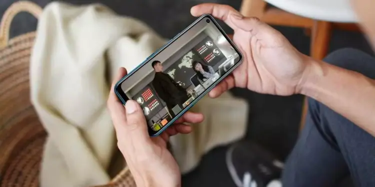 Pengguna smartphone sedang menikmati tayangan video drama dalam posisi landscape di perangkat HP layar berkualitas.