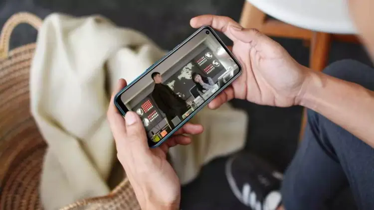 Pengguna smartphone sedang menikmati tayangan video drama dalam posisi landscape di perangkat HP layar berkualitas.