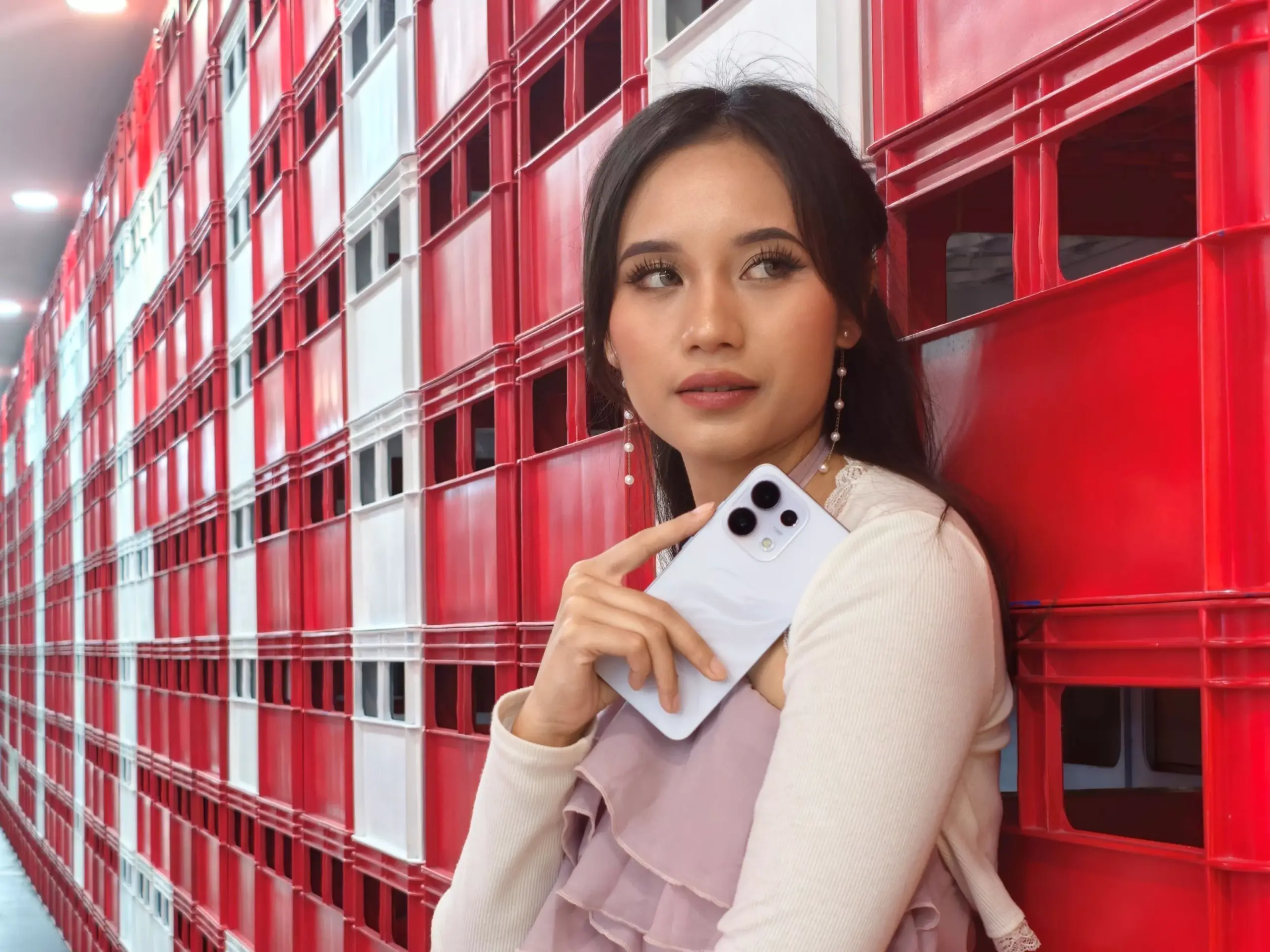Seorang model wanita memegang gawai OPPO Reno16 Series varian warna ungu pastel