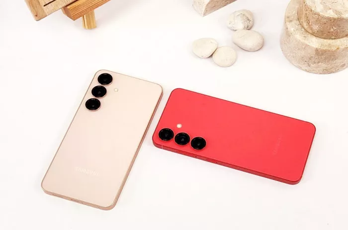 Dua HP Samsung Galaxy kelas flagship berwarna krem dan merah berdampingan di atas meja, bersiap menerima update One UI 9.