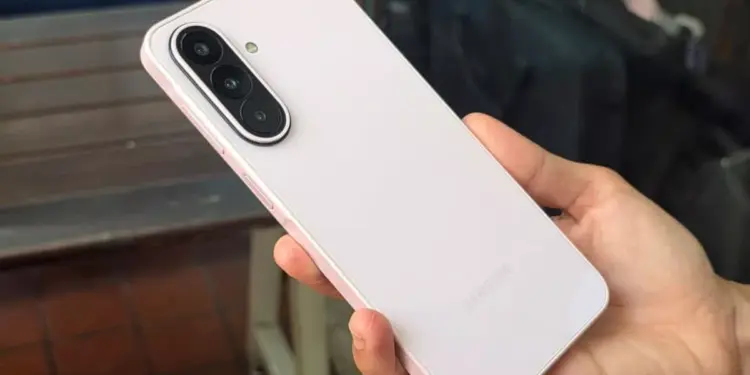 Tampilan bodi belakang Samsung Galaxy A27 5G berwarna merah muda lembut saat digenggam tangan.