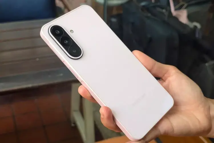 Tampilan bodi belakang Samsung Galaxy A27 5G berwarna merah muda lembut saat digenggam tangan.