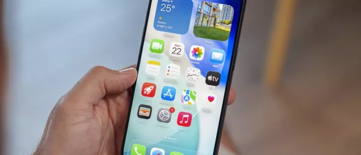 Seseorang sedang memegang perangkat iPhone yang menampilkan antarmuka aplikasi di sistem operasi iOS 26.6.