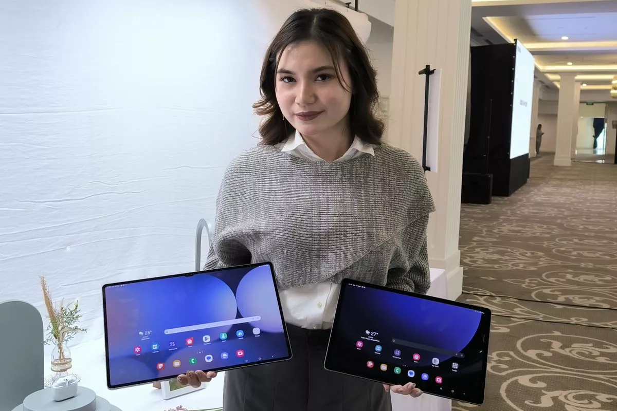Wanita memegang dua pilihan tablet berlayar lebar yang cocok digunakan untuk editing.