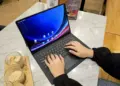 Seseorang sedang mengetik dan mengedit menggunakan tablet berlayar besar di meja cafe.