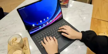 Seseorang sedang mengetik dan mengedit menggunakan tablet berlayar besar di meja cafe.