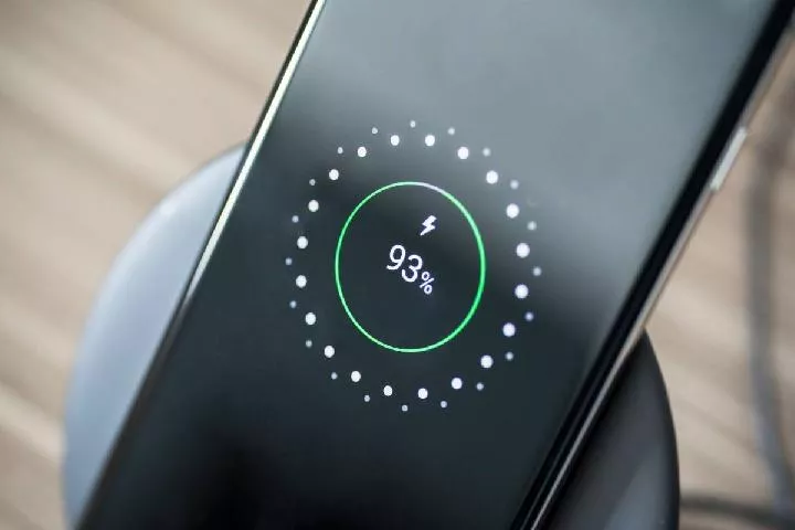 Layar HP Android sedang diletakkan di atas dok wireless charger, menampilkan animasi pengisian daya cepat nirkabel yang sudah mencapai 93%.