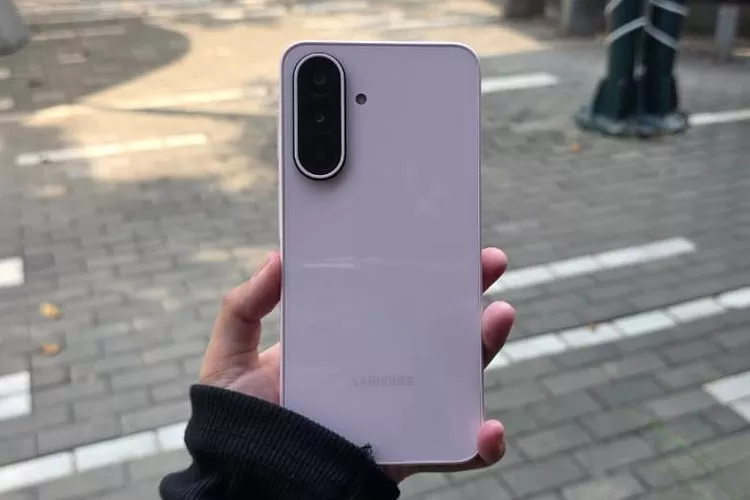 Bagian belakang Samsung Galaxy A27 5G warna ungu muda atau putih saat difoto di area luar ruangan (outdoor).