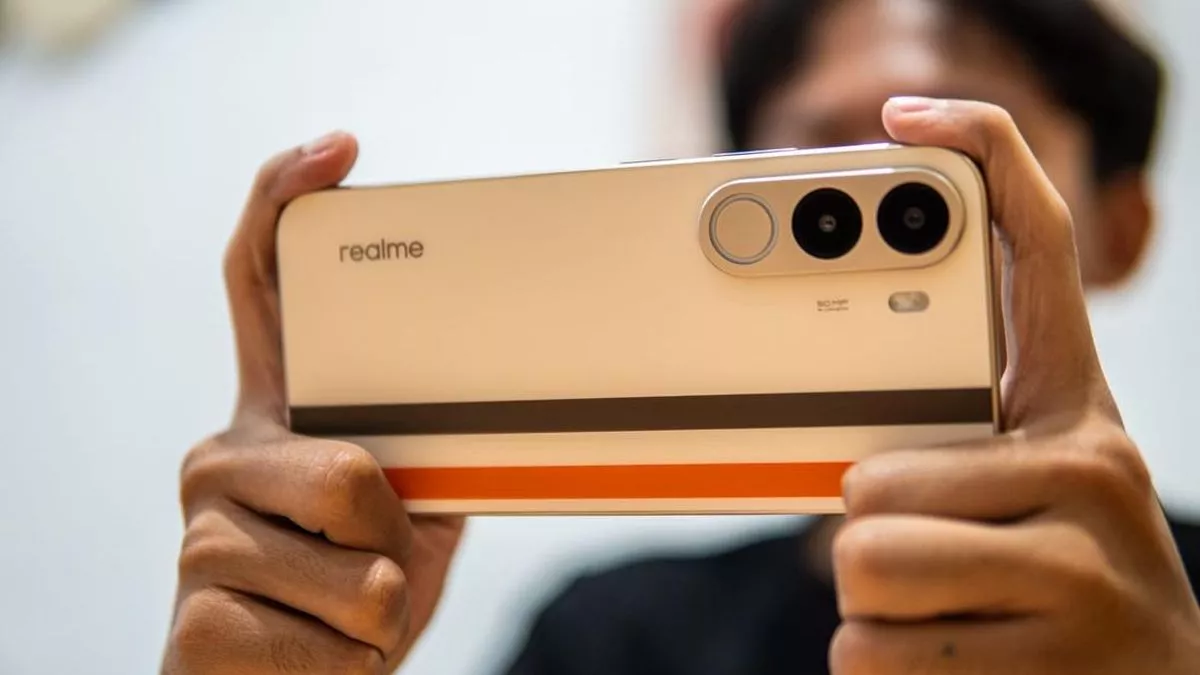 Seseorang memegang HP Realme dengan desain bodi belakang unik dalam posisi lanskap.