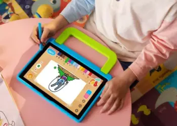 Seorang anak sedang menggunakan stylus pen untuk menggambar di tablet anak murah berukuran 2 jutaan yang dilengkapi casing pelindung tebal berwarna biru-hijau dengan pegangan tangan.