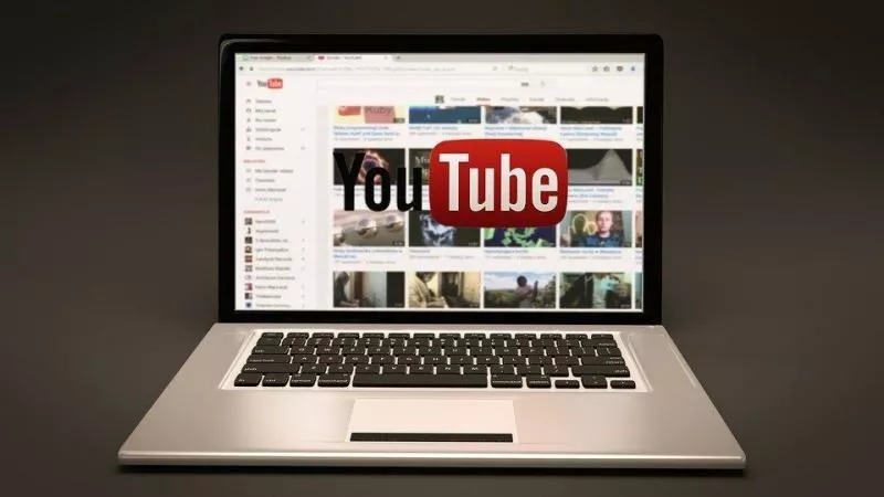 Tampilan halaman utama platform video YouTube di layar laptop perak.