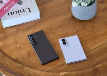 Dua unit Galaxy Z Fold 8 dan Z Flip 8 tergeletak di atas meja kayu di sebelah buku dekorasi.
